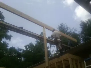 Carpenter setting a ridge beam over a new addition frame — Ice Dam Removal by Roofing Brothers in Burden