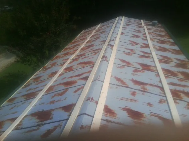 Rusted metal roof panels with new wood purlins before replacement — Storm Damage Roof Repair in Burden by Roofing Brothers