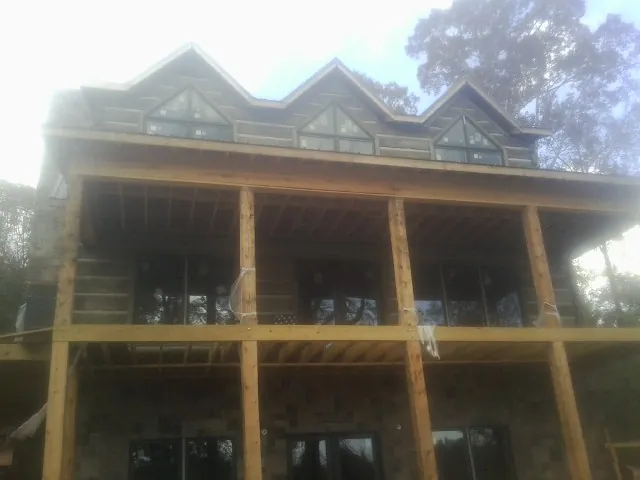 Dormers and porch framing on a large log home under construction — Roof Coating work by our crew in Burden