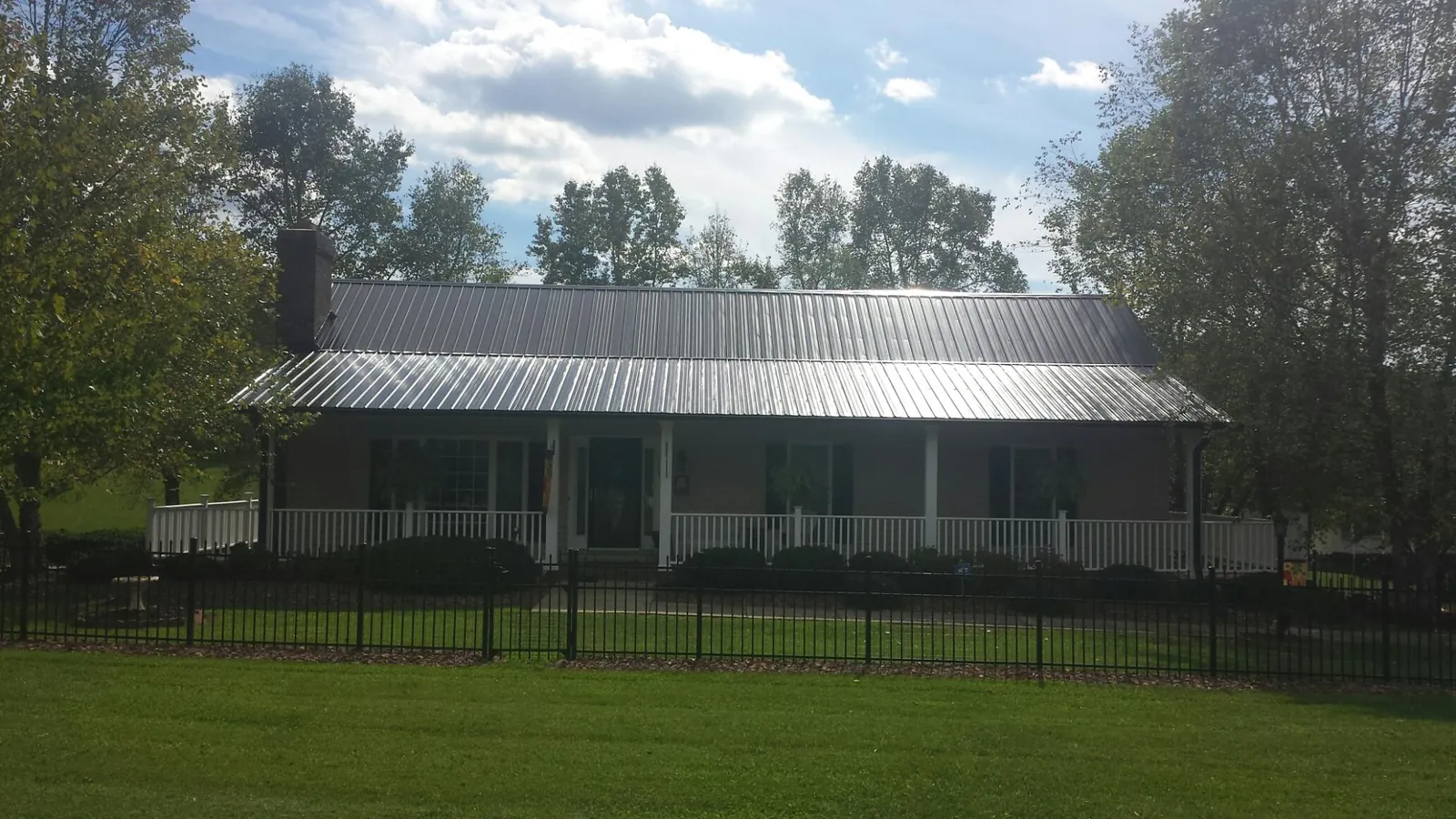 Gray metal roof on a brick ranch with a full width front porch — Gutter Guard Installation work by our crew in Burden