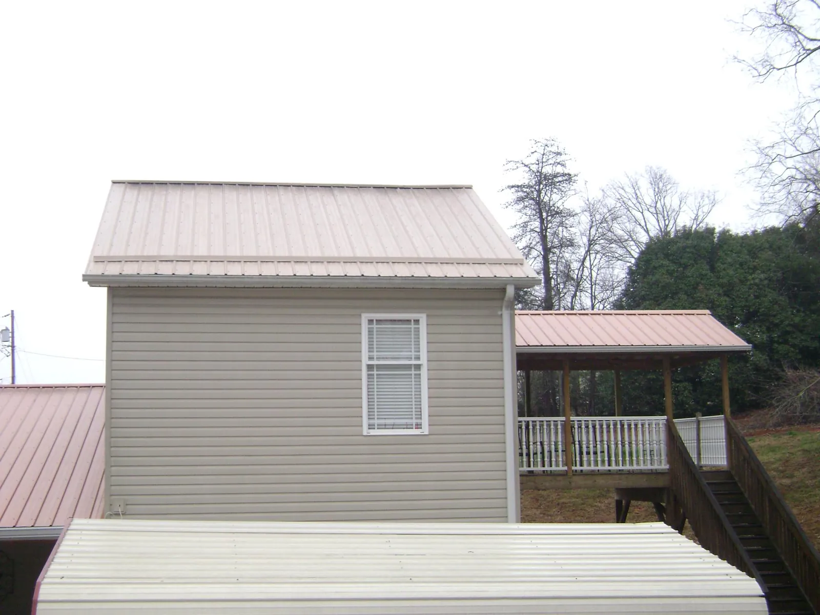 Tan metal roofs on a two story addition and attached porch, from a Roof Replacement job in Burden