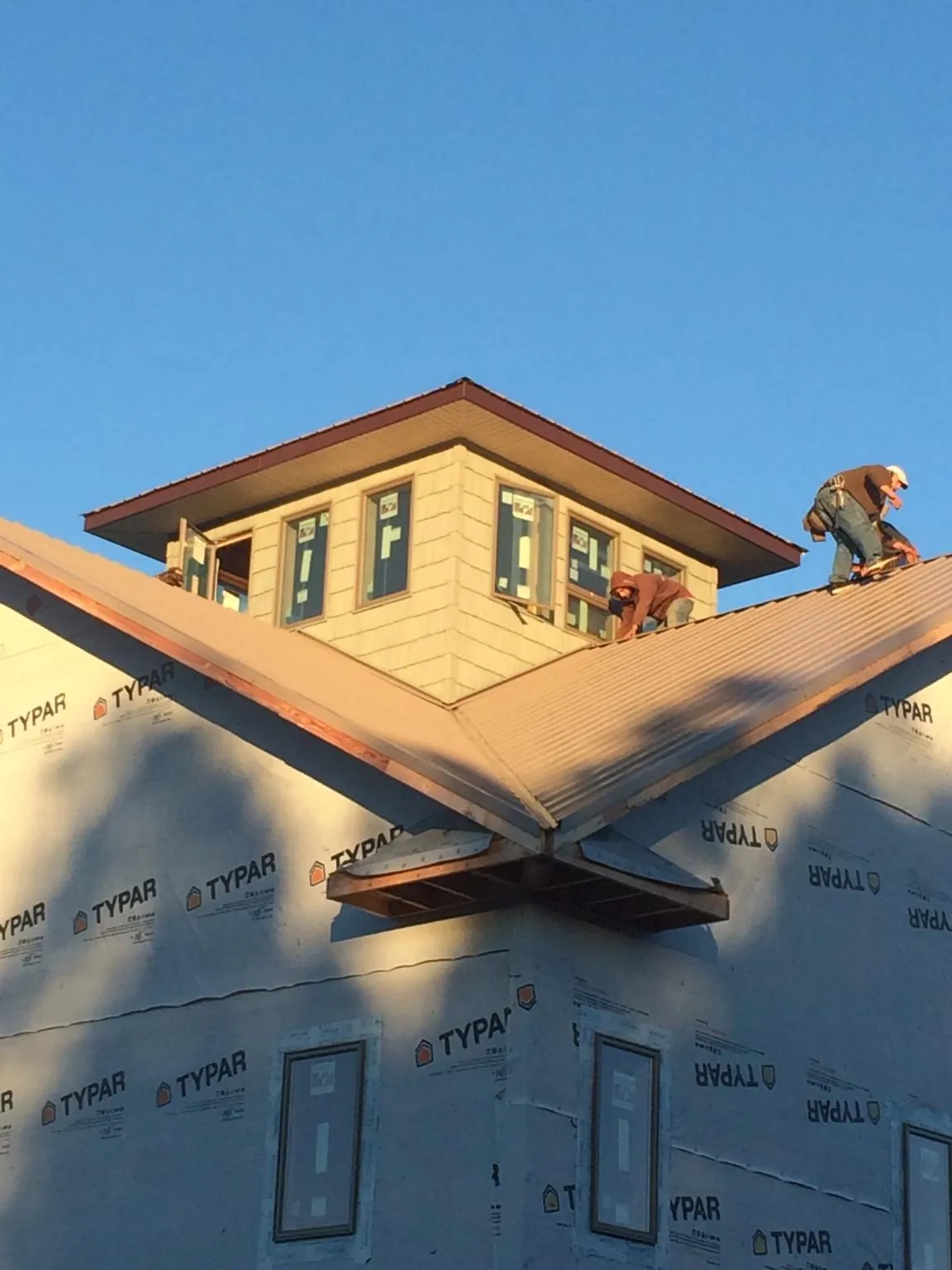 Roofers working around a rooftop cupola on a new metal roof at sunset — Roof Waterproofing in Burden by Roofing Brothers